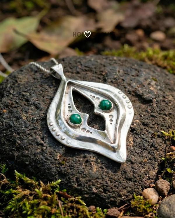 Colgante abstracto y cósmico en plata Elha, tumbado sobre una roca. Joyería energética de Ivan-HoloCosmic.